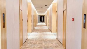 Un largo y estrecho pasillo de hotel con puertas a ambos lados y piso alfombrado.