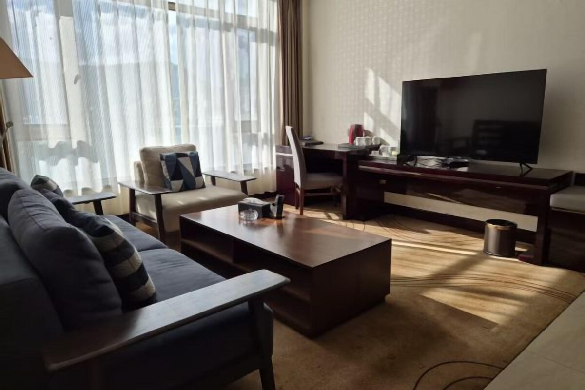 Un salon comprenant un canapé, une table basse, un téléviseur et un bureau avec une chaise.