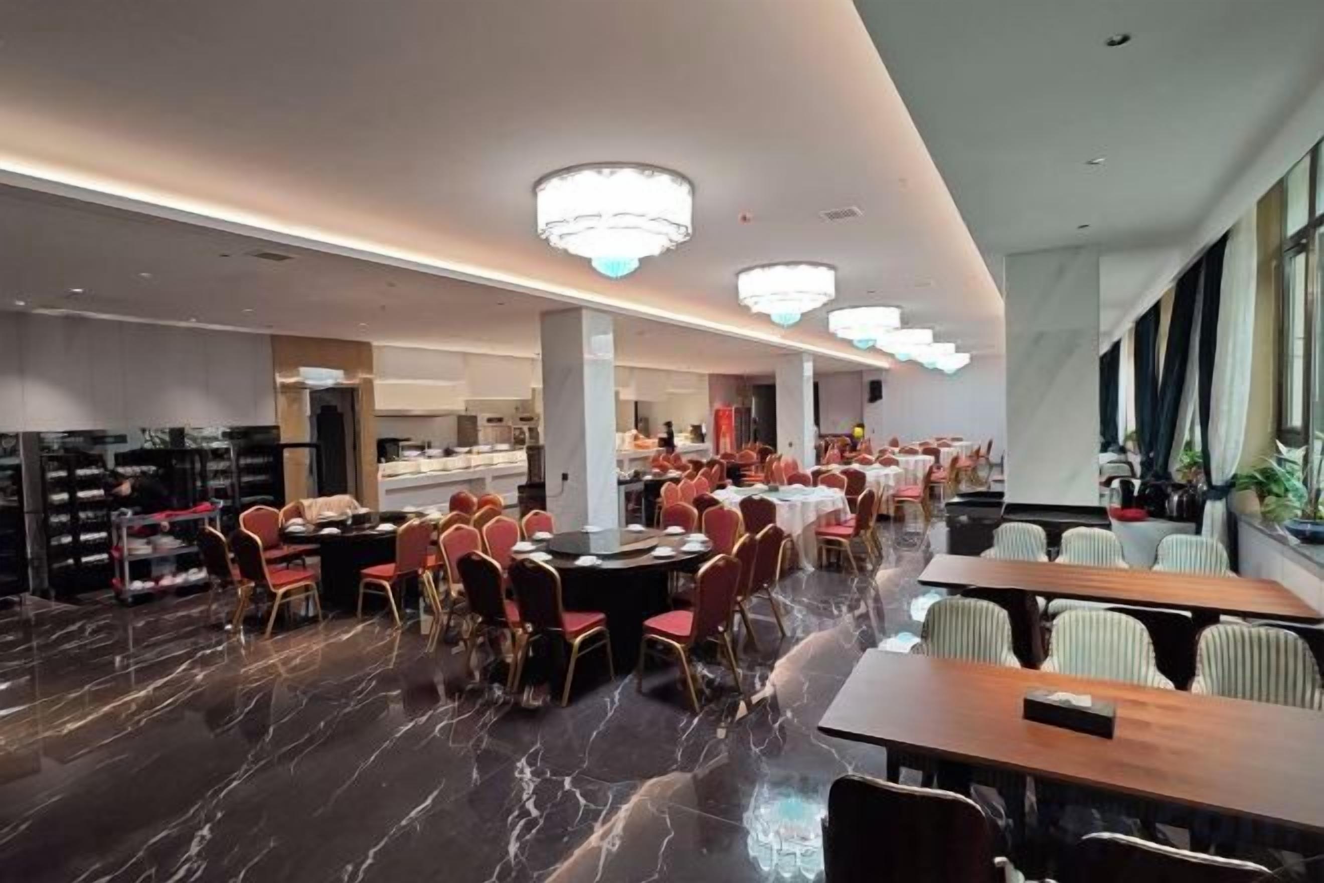 A spacious dining area with multiple tables and chairs, a marble floor, and modern lighting fixtures.