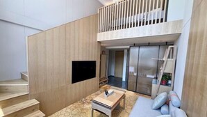 Un interior moderno con una escalera, un televisor de pantalla plana, un sofá y una zona de comedor.