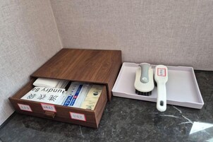 Una caja de madera con compartimentos que contienen libros y un pincel, junto a una bandeja blanca con un pincel y un pequeño recipiente.