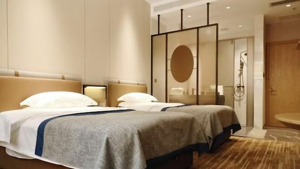 Habitación de hotel con una cama grande, zona de ducha separada y diseño moderno.