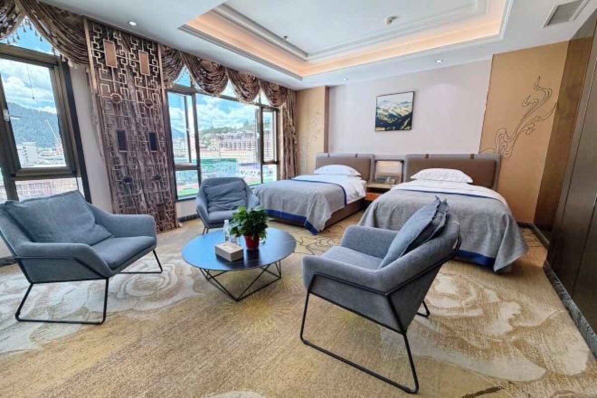 Una habitación de hotel con dos camas, una mesita redonda y dos sillones.