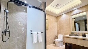 Un baño moderno con ducha de vidrio, inodoro y tocador con espejo.