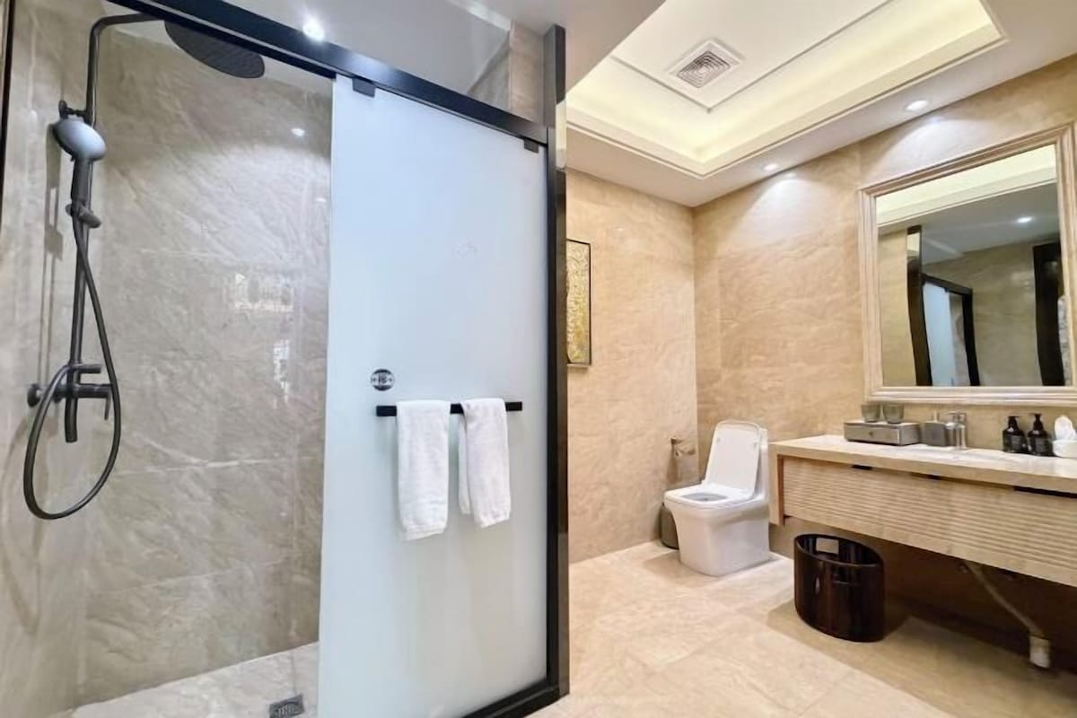 Une salle de bain moderne avec une douche à parois de verre, des toilettes et un meuble-lavabo avec un miroir.