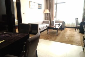 Habitación de hotel con zona de comedor, sofá, mesa de centro y vistas al exterior.