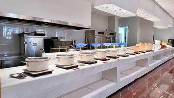 A buffet setup with multiple serving stations, stainless steel appliances, and a marble floor.