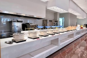 Un buffet avec plusieurs points de service, des appareils en acier inoxydable et un sol en marbre.