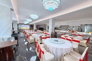 Ein Restaurant mit runden Tischen, weißen Tischdecken und roten Bändern.