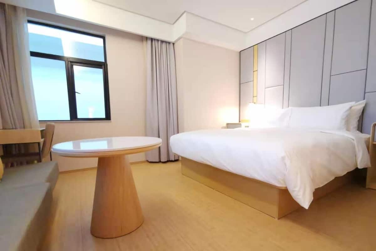 A hotel room with a bed, a round table, and a window.