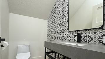 A bathroom with a toilet, a sink, and a mirror.