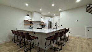 Una cocina moderna con una isla central, taburetes de bar y electrodomésticos integrados.