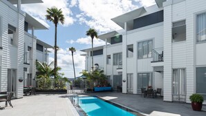 Un hotel moderno con piscina, zona de estar al aire libre y palmeras.
