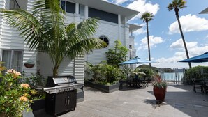 Un patio con una parrilla, mobiliario exterior y palmeras.