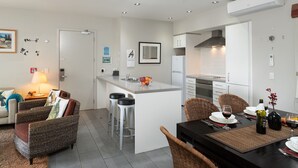 Una cocina moderna con una isla central, taburetes de bar y una mesa de comedor para dos.