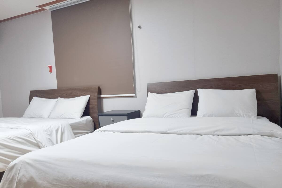 Two single beds with wooden headboards, a nightstand, and a wall-mounted light fixture.