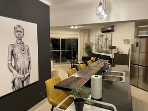 A modern dining area with a long table, yellow chairs, and a chandelier. - 3D View: Ocean & City Views from Each Balcony+Pool (LA JULIA)