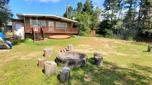 A cabin with a deck, a fire pit, and a boat in the background. - Coos bay - Lake house - Direct Dune access - Saunders Lake - Oregon Dunes (North Bend)