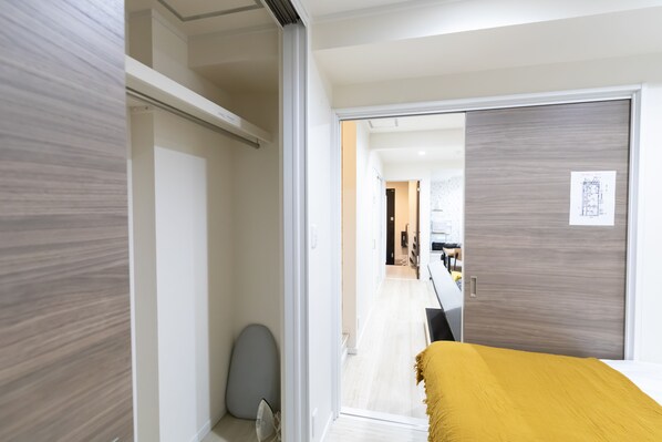 A modern hotel room with a bed, a wardrobe, and a door leading to a hallway.