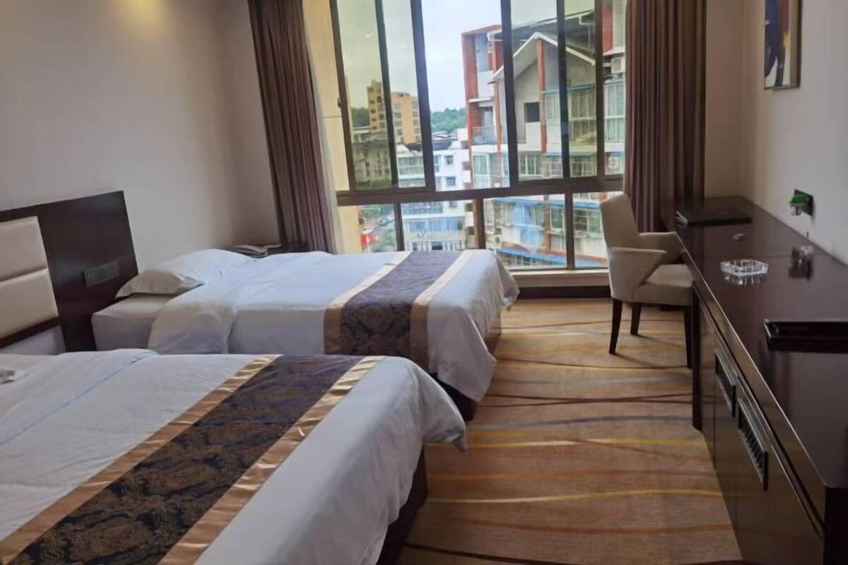 Habitación de hotel con dos camas, un escritorio y una silla.