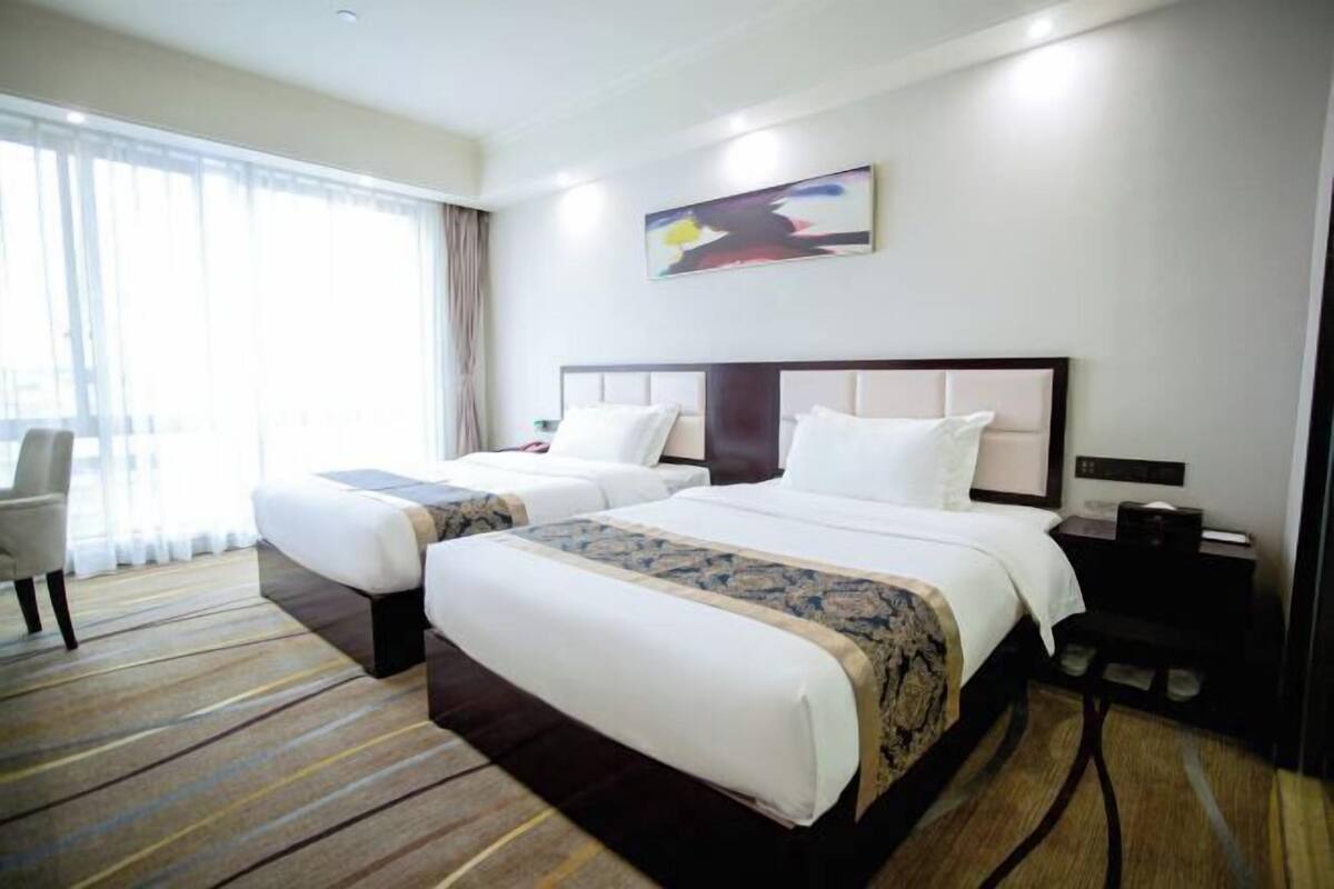 Habitación de hotel con dos camas, un escritorio y una silla.