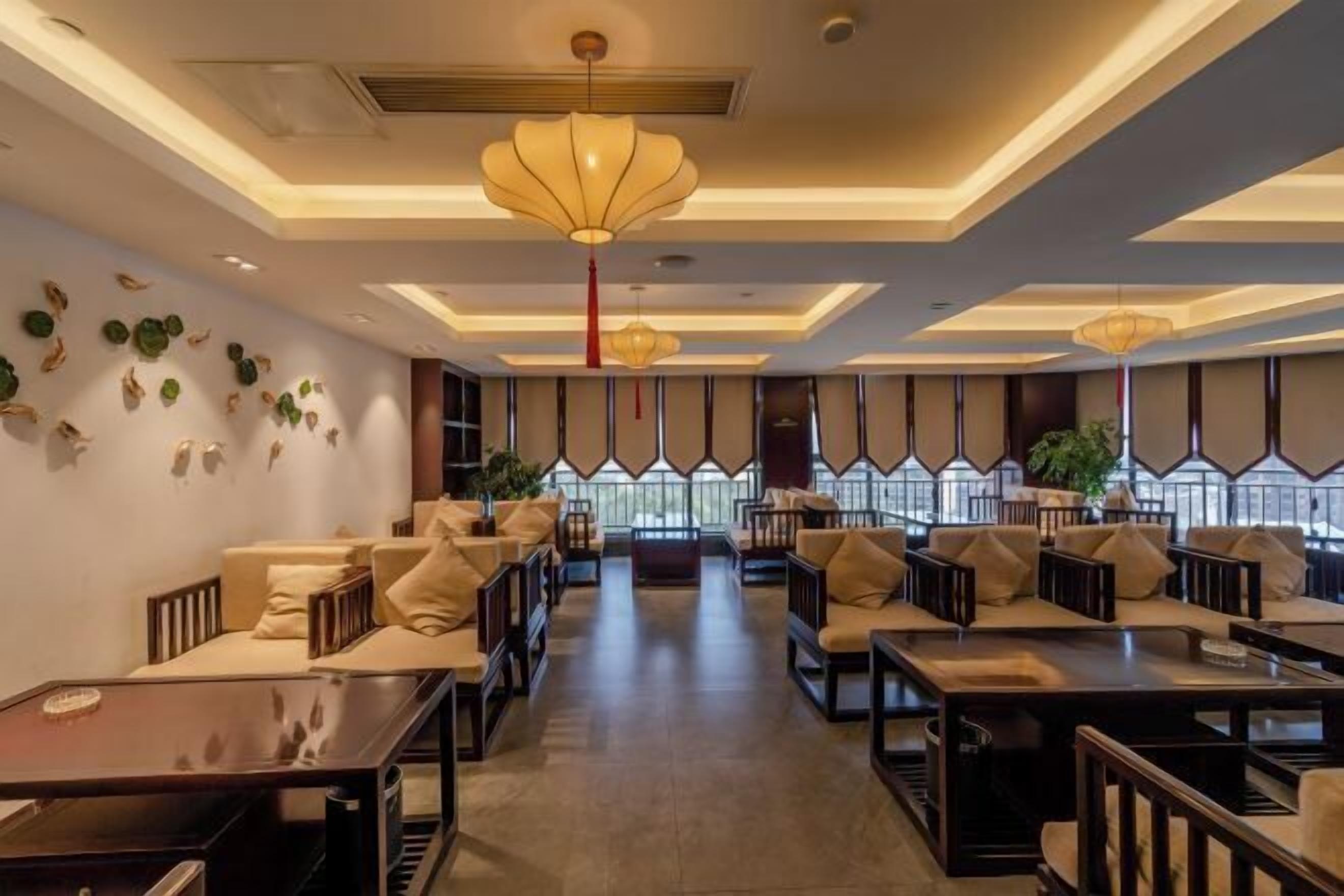 A modern hotel lobby with seating areas, large windows, and decorative wall elements.