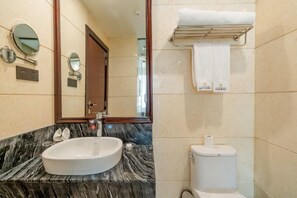 Een badkamer met een marmeren wastafel, een toilet, een handdoekhouder en twee spiegels aan de muur.