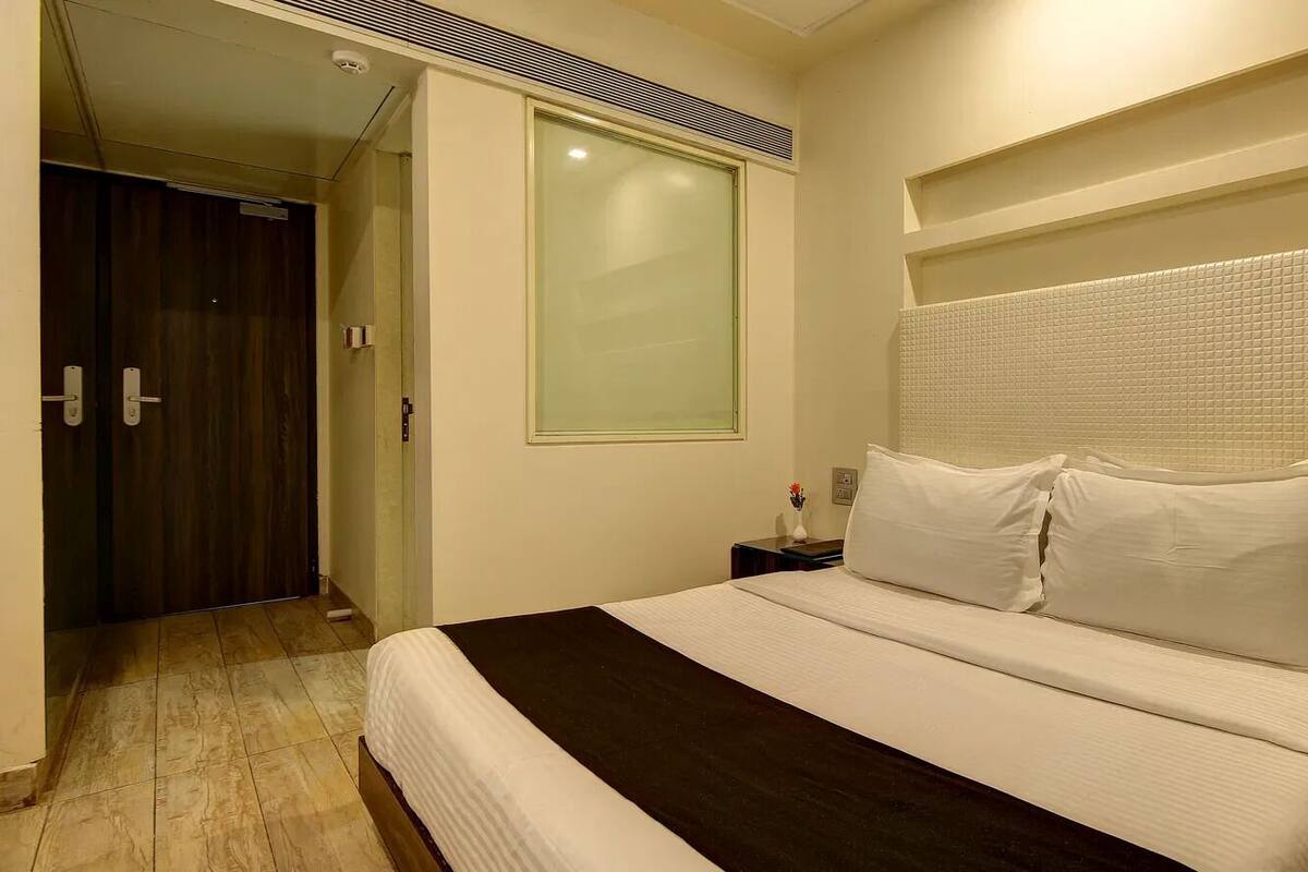 Ein Hotelzimmer mit einem großen Bett, einem Nachttisch, einem Fenster und einer Tür.