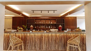 A bar area with a wooden slatted counter, two wicker chairs, and shelves stocked with bottles and glasses. - Isla Amara Resort (El Nido)