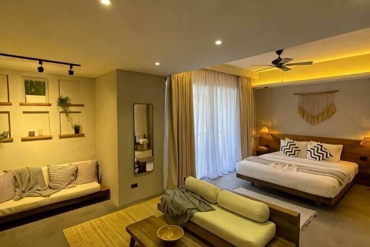 Ein modernes Hotelzimmer mit Sofa, Bett, Couchtisch und Deckenventilator.