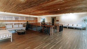 A spacious lobby with a wooden ceiling, a white reception desk, a seating area with sofas, and a staircase. - Isla Amara Resort (El Nido)