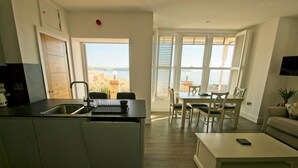 Una cocina moderna con una isla integrada, un comedor con mesa y sillas, y vista al mar.
