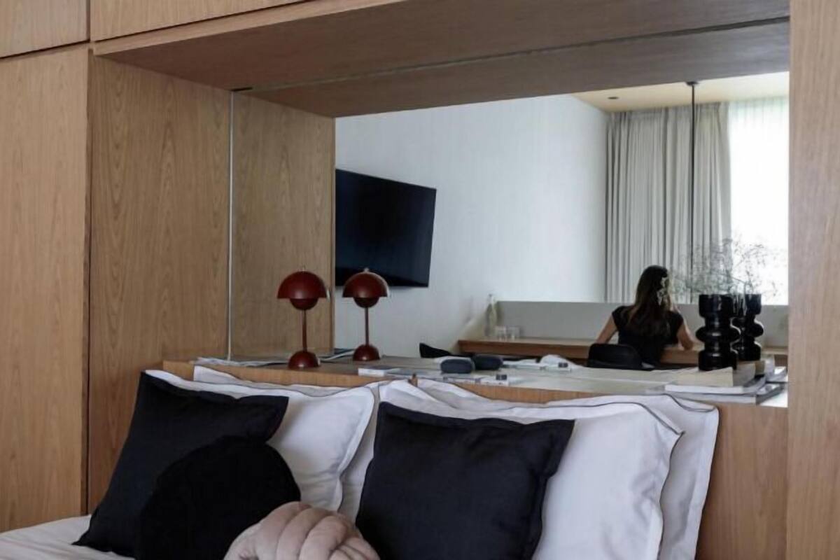 Een moderne hotelkamer met een bed, nachtlampjes, een bureau en een grote spiegel.
