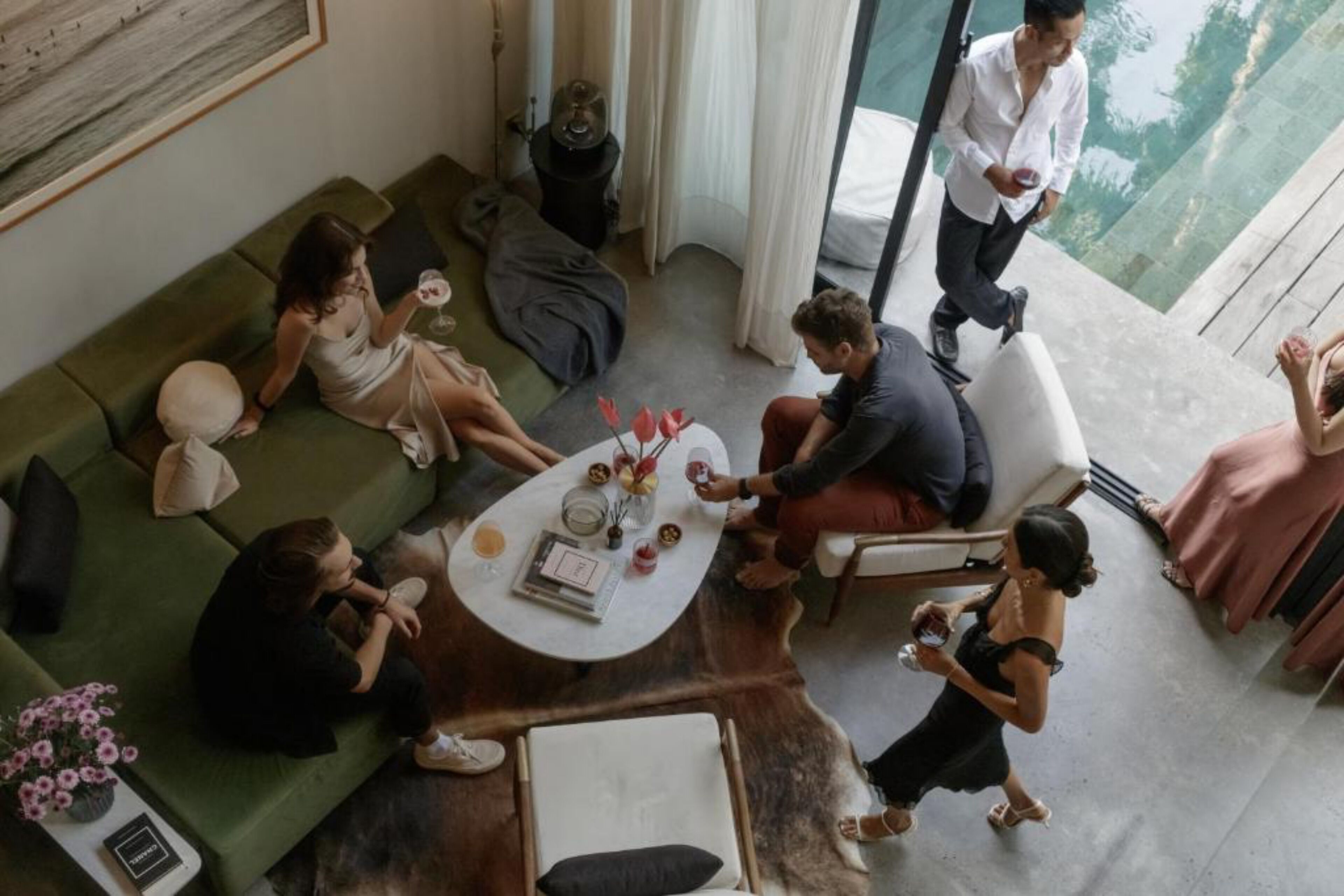A modern living room with a green sofa, a coffee table with decorative items, and a view of the outdoors through large windows.