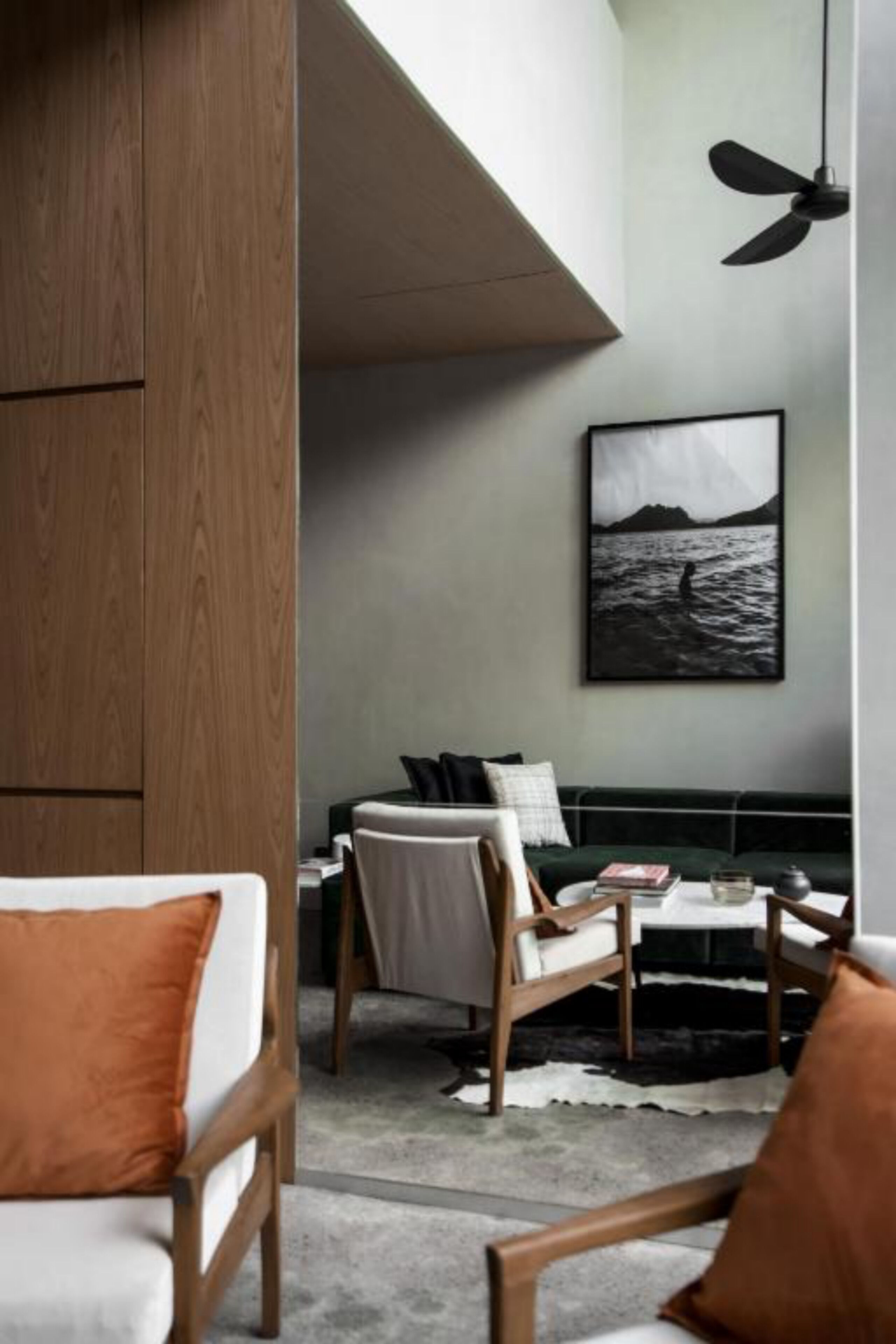 A modern living room with a sofa, chairs, a coffee table, and a ceiling fan.