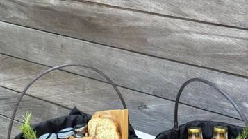 Two wicker baskets filled with food items and drinks, placed on a table against a wooden backdrop.