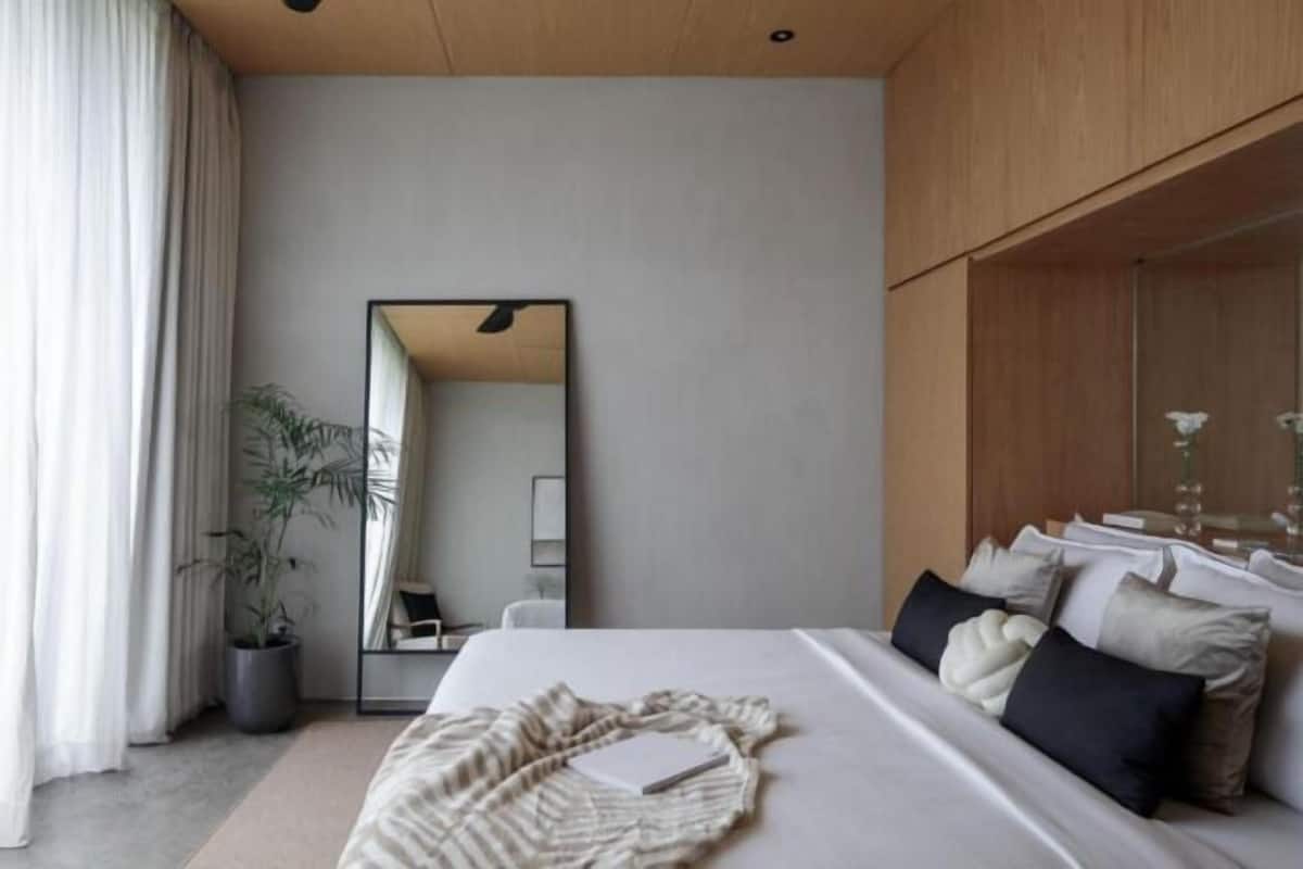 Een moderne hotelkamer met een groot bed, nachtkastje, spiegel en een potplant.