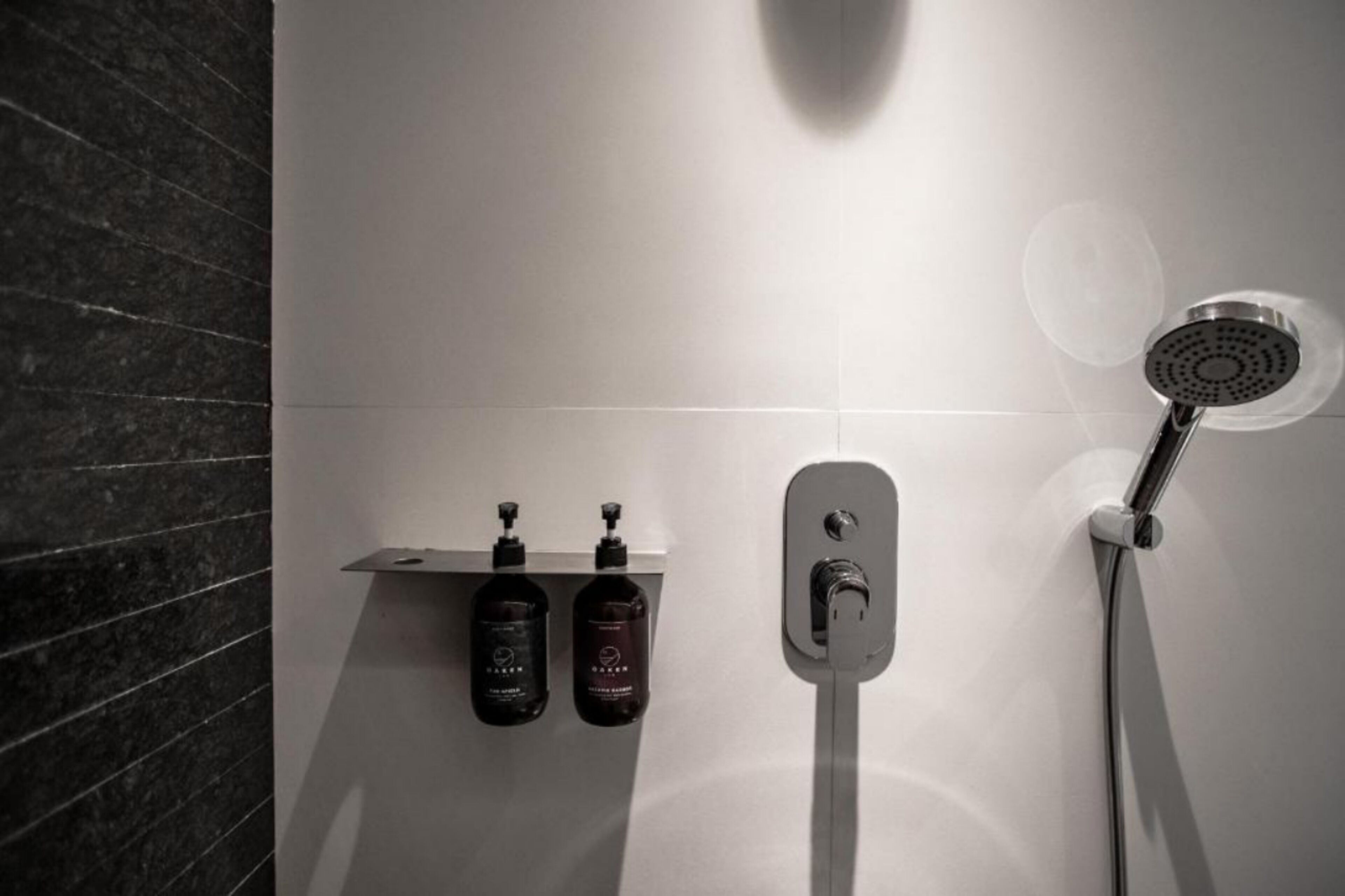 A modern bathroom with a shower, two bottles of shampoo, and a towel rack.