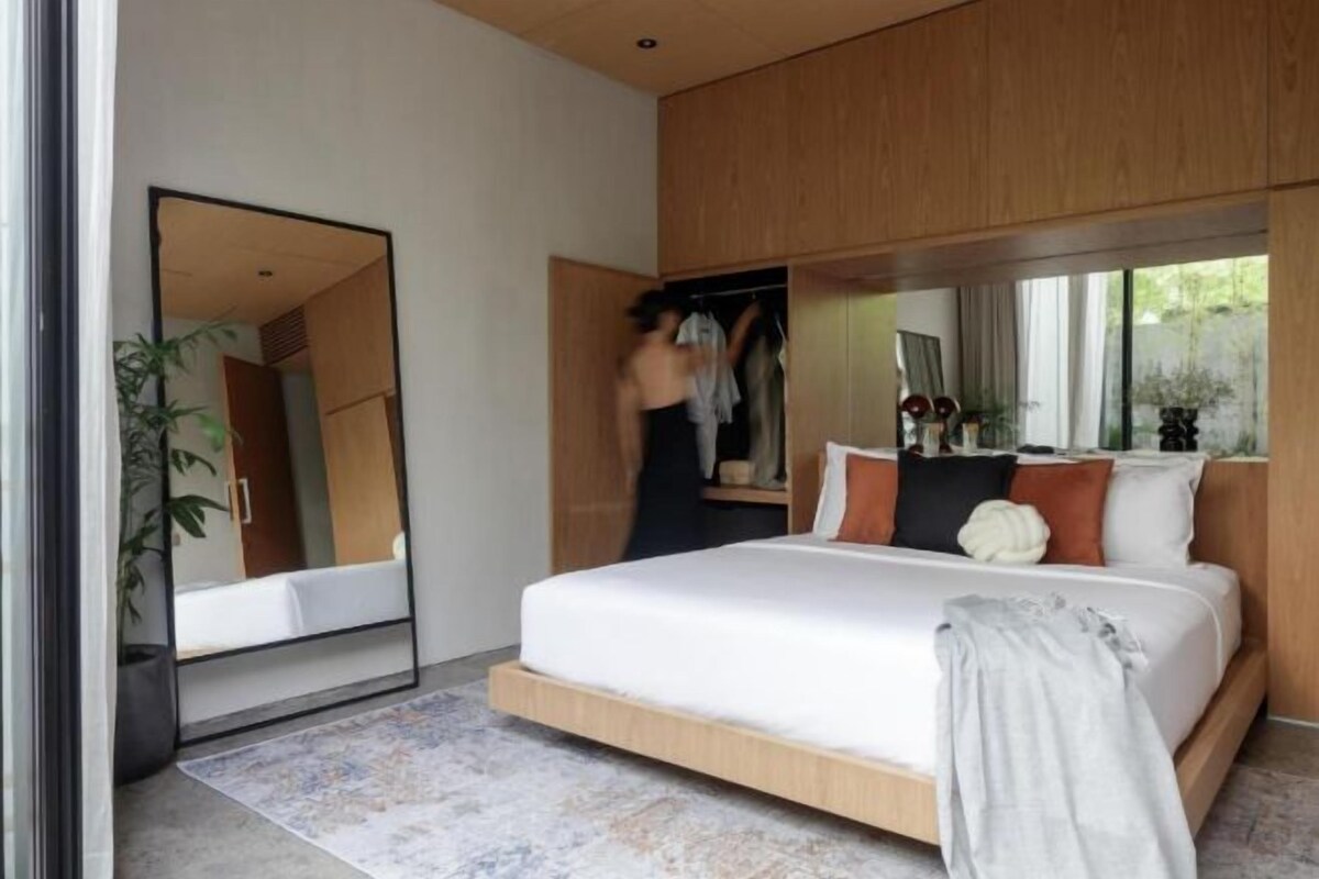 Une chambre moderne avec un grand lit, une armoire, un miroir et une fenêtre.