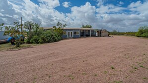 A single-story building with a gravel driveway and a clear blue sky. - Newly updated home on spacious lot located outside of the city (Apache Junction)