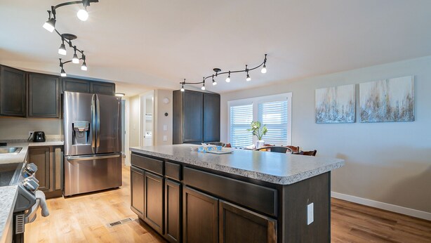 A modern kitchen with dark cabinetry, stainless steel appliances, and a granite countertop. - Newly updated home on spacious lot located outside of the city (Apache Junction)