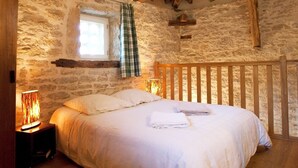 Une chambre rustique avec un lit en bois, des murs en pierre et un plafond en pente.