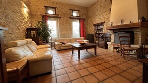 Un salon chaleureux avec un mur en pierre, une cheminée, un canapé, une table basse et une bibliothèque.
