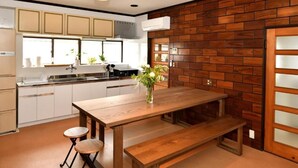 Uma cozinha com mesa de madeira, dois bancos e um assento.