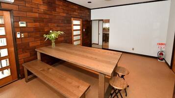 A room with a wooden table and bench, a small plant on the table, and a fire extinguisher on the wall.
