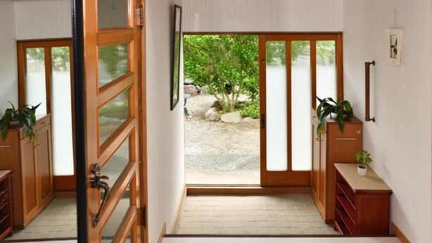 Quarto com porta de vidro deslizante que dá para um jardim, armários de madeira e uma pequena mesa com uma planta.