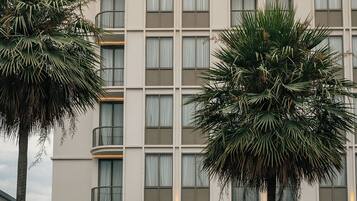 A hotel named "Hotel Moco" with a modern facade, multiple windows, and a prominent entrance with a large door and decorative elements.