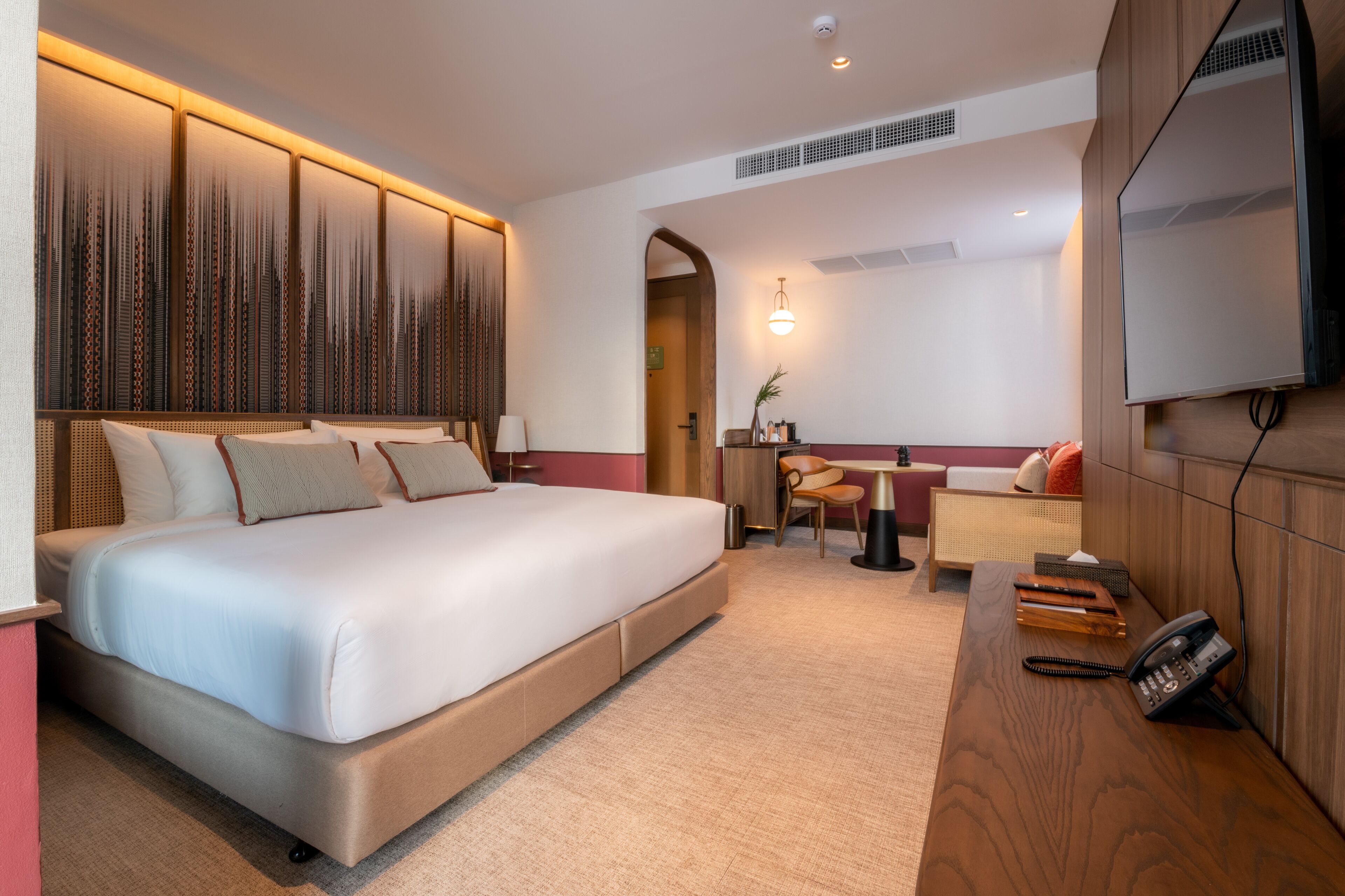 Une chambre d’hôtel moderne, dotée d’un grand lit, d’un bureau et d’une télévision.