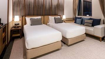 A hotel room with two beds, a sofa, a large window with curtains, and a decorative wall panel.