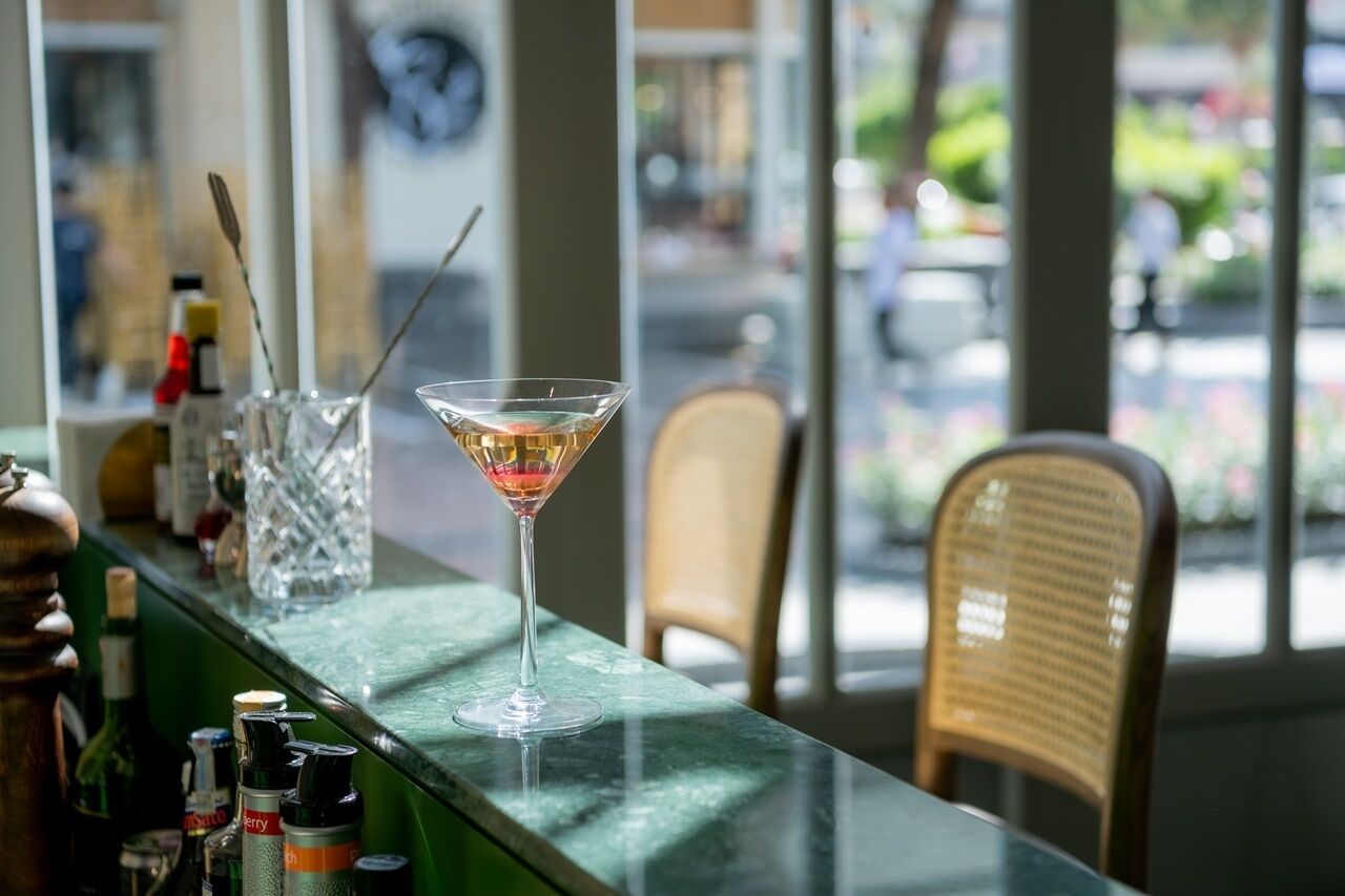 Un coin bar avec un verre à martini, des bouteilles et un fauteuil en osier.